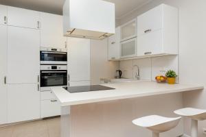 a white kitchen with white cabinets and appliances at Siedmiogrodzka Apartment with Balcony & Parking Warsaw Wola by Renters in Warsaw