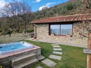 uma casa de pedra com uma banheira de hidromassagem num quintal em Vallibona Pool's Depandance em Castiglion Fiorentino