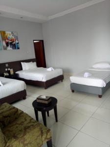 a hotel room with three beds and a table at Hotel Sindha in Ruteng