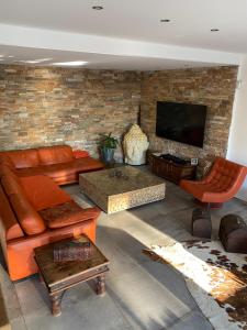 ein Wohnzimmer mit orangefarbenen Möbeln und einer Ziegelwand in der Unterkunft Villa Lina in Cuers