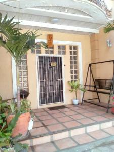 Chelsiefaye Guest House في لواوْغ: باب أمام منزل به نباتات الفخار