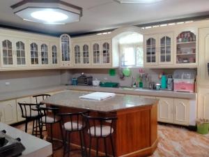 Chelsiefaye Guest House في لواوْغ: مطبخ مع دواليب بيضاء وجزيرة مع كراسي بار