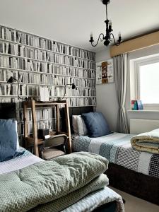 a bedroom with two beds and a wall of books at Woodbriar in Penmaen-mawr