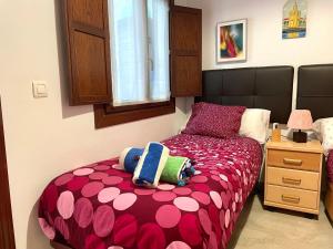 セビリアにあるApartamento Centro Plaza Salvador, Wifi free& parking opcionalのベッドルーム1室(赤とピンクの掛け布団付きのベッド1台付)