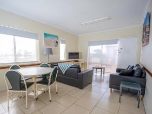 - un salon avec un canapé, une table et des chaises dans l'établissement API Pelican Beach Front Apartments Kalbarri, à Kalbarri