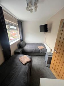 um pequeno quarto com 2 camas e uma janela em 2 bed semi-detached house em Warrington