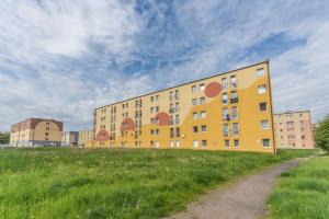 a yellow building on top of a grass field at Hello Apartments Brzeźno Dworska DARK in Gdańsk