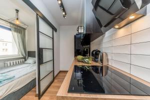a kitchen with a sink and a bed in a room at Hello Apartments Brzeźno Dworska DARK in Gdańsk