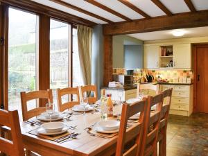 a dining room with a table with chairs and a kitchen at Chalgrove in Aber-Brân