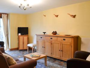 a living room with a tv and a wooden cabinet at Chalgrove in Aber-Brân