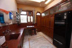 a kitchen with wooden cabinets and a black refrigerator at Kapoor Sahab Homestay : it's a home away from home. in Varanasi