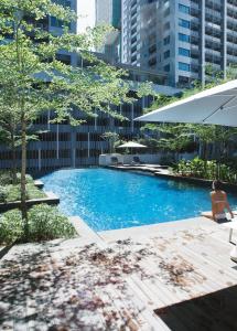 a woman sitting next to a swimming pool in a city at Sfera Residence Kuala Lumpur City Centre in Kuala Lumpur