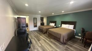 a hotel room with two beds and a flat screen tv at Garden Inn and Suites Glendora in Glendora