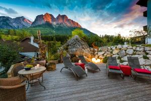 a deck with chairs and a fireplace with mountains at Bayern Resort Hotel (Adults only) in Grainau