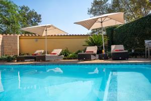 ein Pool mit zwei Sonnenschirmen und Stühlen daneben in der Unterkunft Golden Horse Hotel 