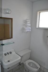 Baño blanco con aseo y lavamanos en Travel Inn Motel Michigan City, en Michigan City