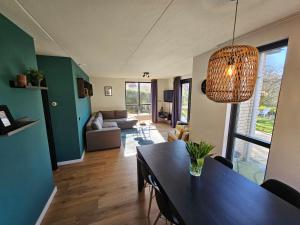 ein Wohnzimmer mit Tisch und ein Esszimmer in der Unterkunft 7 person House with garden, firepit, swimming lake, hammock, child friendly, in- and outside playground, slide, and great coffee in Ewijk