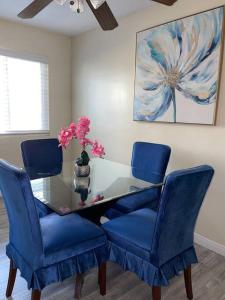 a dining room table with blue chairs and a vase with flowers at SUITE Queen Apart South-Bay Beaches in Gardena