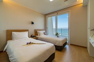 two beds in a room with a large window at Gangneung PINEART Label in Gangneung