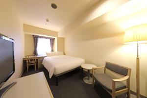 una camera d'albergo con letto e sedia di Shin-Yokohama Kokusai Hotel a Yokohama