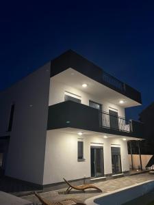 a large white building with a balcony at night at LuxVilla AURORA in Vodice