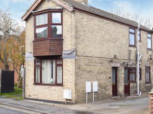 una vieja casa de ladrillo al lado de una calle en High Street Apartment, en Kessingland