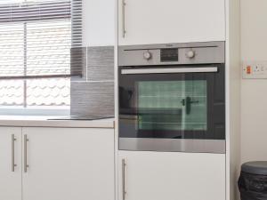 cocina con armarios blancos y horno en High Street Apartment, en Kessingland