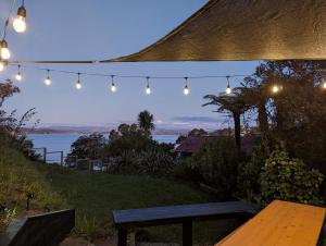 a bench sitting under a tent with lights at Cox Bay Cottage in Raglan