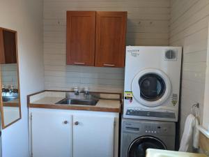 a kitchen with a sink and a washing machine at Cox Bay Cottage in Raglan