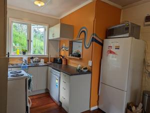 a kitchen with a white refrigerator and a microwave at Cox Bay Cottage in Raglan