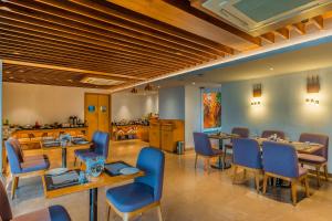 um restaurante com cadeiras e mesas azuis numa sala em De Mandarin Candolim Beach Goa em Candolim