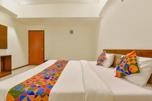 a bedroom with a large white bed with colorful pillows at FabHotel Shivam, Karelibagh in Vadodara