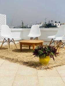 three white chairs and a table on a rug at Lovely 2 bedrooms appartment with rooftop in Temara