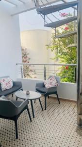 d'un balcon avec des chaises, une table et une fenêtre. dans l'établissement Lovely 2 bedrooms appartment with rooftop, à Temara