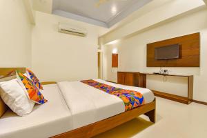 a bedroom with a bed and a tv on the wall at FabHotel Shivam, Karelibagh in Vadodara