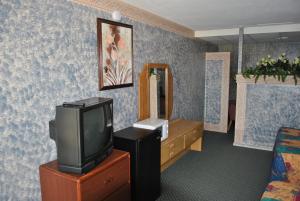 Habitación con TV en un tocador y espejo. en Travel Inn Motel Michigan City, en Michigan City