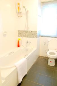 ein weißes Bad mit einer Badewanne und einem WC in der Unterkunft The Inn Saladaeng in Bangkok