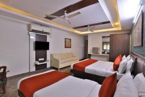 a hotel room with two beds and a couch at Hotel Sadbhav in Ahmedabad
