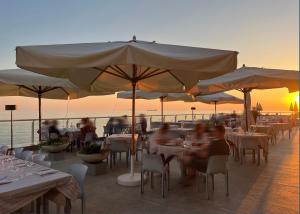 a group of people sitting at tables under an umbrella at Hotel Rex in Livorno