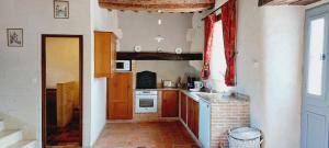 a kitchen with wooden cabinets and a brick floor at Le domaine des Roseraies, in Monfréville +45 photos