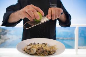 a person holding a lime over a plate of food at Hotel Rex in Livorno