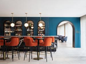 a bar with orange chairs and a blue wall at Hyatt House London Stratford - Aparthotel in London