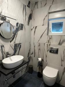 een badkamer met een wastafel, een toilet en een spiegel bij LuxVilla AURORA in Vodice