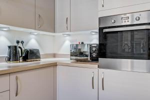una cocina con armarios blancos y horno negro en Beautiful and Comfortable Home away from Home en Northampton