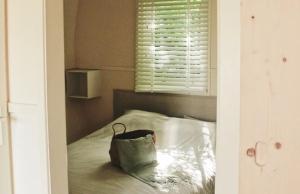 un sac assis au-dessus d'un lit avec une fenêtre dans l'établissement CoCon, à Scharendijke
