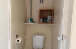 a bathroom with a toilet with a shelf above it at CoCon in Scharendijke