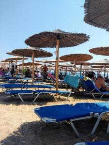 eine Gruppe von Stühlen und Sonnenschirmen am Strand in der Unterkunft Angel Room 1 in Nea Plagia