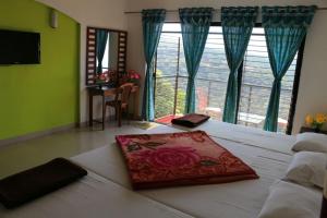 een slaapkamer met een bed met een rode deken erop bij HOTEL MAHARAJA VALLEY in Mahabaleshwar