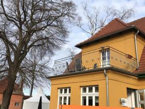 a yellow house with a balcony on top of it at Große Ferienwohnung Klosterklause Malchow in Malchow