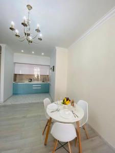 a white dining room with a white table and chairs at Жк Арман двухкомнатная квартира в центре города/ Zhk Arman one-bedroom apartment in the city center in Atyraū